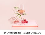 Rose wine. Minimalistic, Summer, holiday composition with glass of rose wine, grapes and palm leaf on a pink tray on a pink background. Self-partnered and self love concept