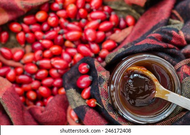 Rosehip Berries On Fabric Terracotta Color And A Wooden Spoon With Jam