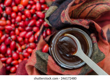 Rosehip Berries On Fabric Terracotta Color And A Wooden Spoon With Jam