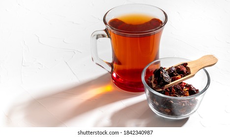 Rosehip Tea In A Clear Glass Mug And Dried Rosehips In A Small Cup. Copy Space.