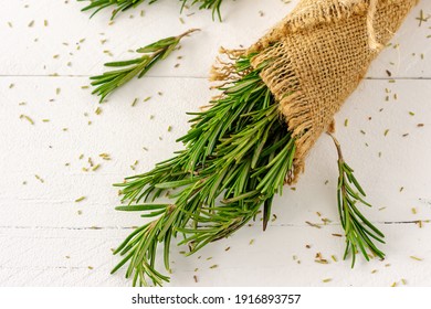 Rosemary bound in burlap cloth on a wooden white board.