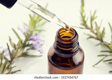 Rosemary Essential Oil. Close Up Of A Pipette, Amber Bottle And Rosemary Branch At Background. Herbal Remedies