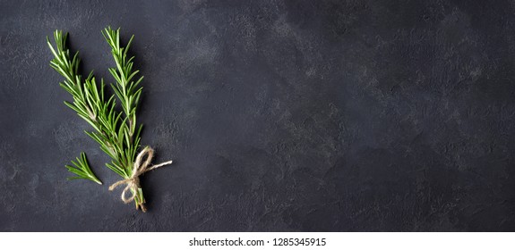 Rosemary herbs on dark stone background. Copy space for menu or recipe. Flat Lay.
