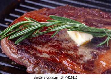 Rosemary And Melting Butter Lay On Grilled Steak Of Marble Beef Ribeye Frying In Grill Pan