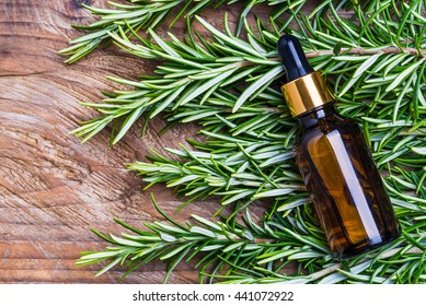 Rosemary oil bottle on wooden background copy space. Essential oil, aromatherapy natural remedies.