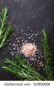 Rosemary, Pink Salt And Spices On Black Stone Table Top View With Copy Space For Menu Or Recipe, Flat Lay.