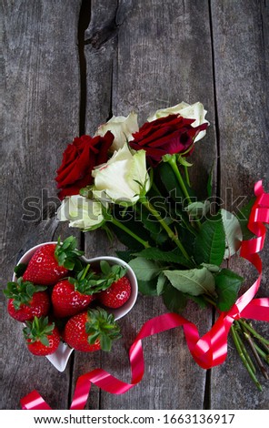 roses and strawberries on dar woodensurface