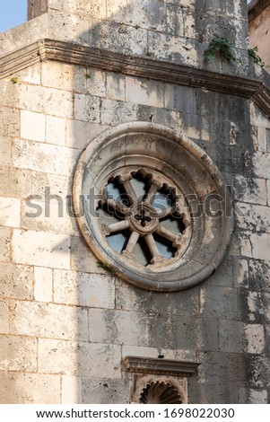 A rosette on the facade of an old Cathalic church made out of limestone in Korcula city at the main square in Dalmatia, Croatia on a sunny day. Tourist destination