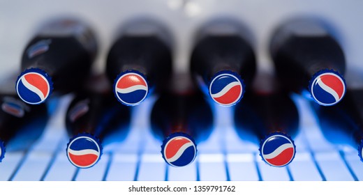 Roseville, CA / USA - April 04 2019: Vintage looking glass Pepsi bottles filled with the beverage Pepsi, unopened, in an ice cold refrigerator with blue back light