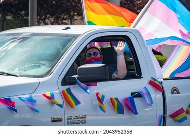 ROSEVILLE, CA, U.S.A. - SEPT. 19, 2021: Atom Vaughn, a trans man, waves in rainbow beard as he drives his decorated pickup truck with rainbow and transgender flags during Placer Pride caravan event.