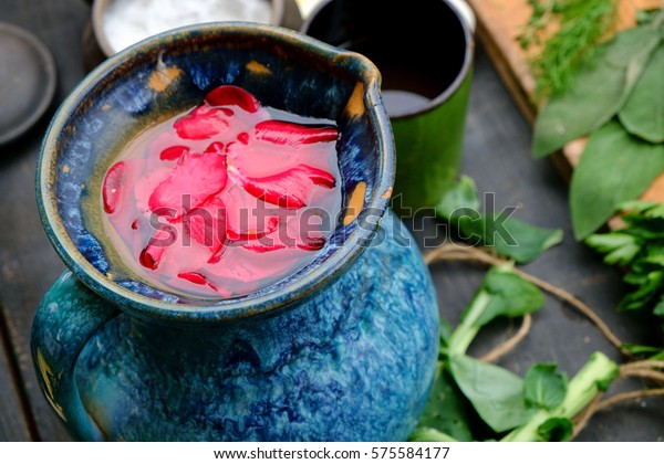 Rosewater in blue jug. Water with\
rose petals in blue clay jug for culinary, perfumes and skin\
care.