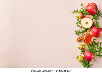 Rosh Hashana, jewish new year holiday concept with traditional symbols, apples, honey, pomegranate on a pastel pink, coral table. Flat lay, copy space background