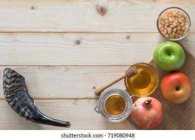 Rosh Hashanah (Hashana)  (jewish New Year Holiday) And Yom Kippur Concept With Ram Shofar (horn) And Traditional Food, Apple, Honey, Pomegranate Fruit Flat Lay On Wood Table Background From Top View