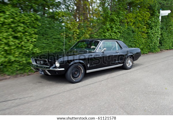 ROSMALEN, THE\
NETHERLANDS - MAY 16: Black 1967 Ford Mustang HTP Coupe arriving on\
the Rock Around the Jukebox Open Air event on May 16, 2010 in\
Autotron Rosmalen in\
Holland.