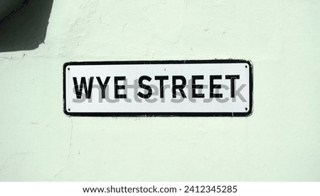 Ross On Wye, Herefordshire, England Sept 24 2023:  Street name sign: Wye Street named after the River Wye which winds its way around this historic town. A white sign, black letters, pale green wall.