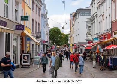 ROSTOCK, GERMANY - 03. August 2021: People In The Inner City On The Shopping Street. Tourists In The Town Enjoying The Day. A Lot Of Stores With Their Advertisement On The Facades Are Visible.