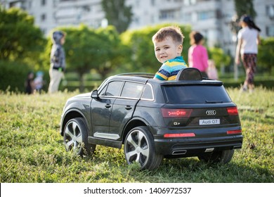 Rostov-on-Don, Russia, 18.05.2019 : Cute 3 year old boy in  is riding a black  electric car audi q7 in the park featuring a vibrant emotions, laughter and smile