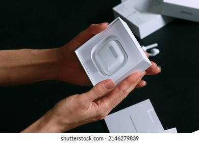 ROSTOV-ON-DON, RUSSIA - Apr.03 2022: Human Hands Unpacking New Model AirPods On The Black Background. The Box From Previous Release Of Apple Earphones Lying Down On Back Stage. Copy Space.