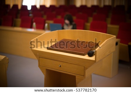 rostrum with a microphone in a reference room with one person at background