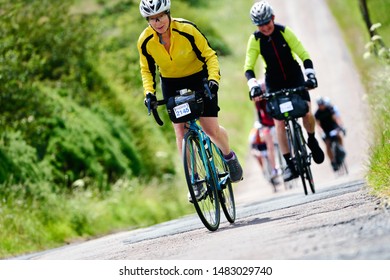 ROTHBURY, NEWCASTLE UPON TYNE, ENGLAND, UK - JULY 06, 2019: An Older Female Cyclist Pedaling Up A Steep Hill In The Cyclone Race Event Starting In Newcastle And Going Through Northumberland.