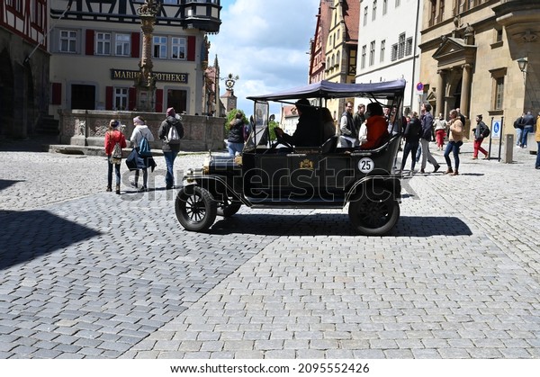 Rothenburg ob der Tauber, Germany\
- 05 23 2021: A historical tourist car in the historical city of\
Rothenburg ob der Tauber, Germany. Tourists are in the\
background.