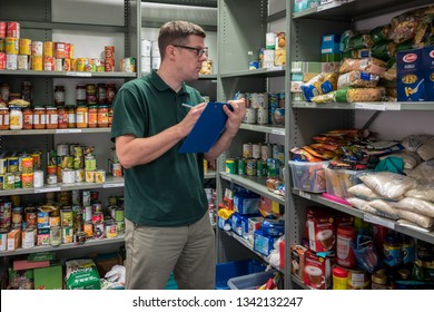 ROTHERHAM, ENGLAND, UK - FEBRUARY 14, 2019: A Volunteer Man Working At A Trussell Trust Local Church Food Bank Checks Donations With A Clipboard And Packing Slip