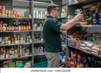 ROTHERHAM, ENGLAND, UK - FEBRUARY 14, 2019: A Volunteer Man Working At A Trussell Trust Local Church Food Bank Organises Donations On Shelves