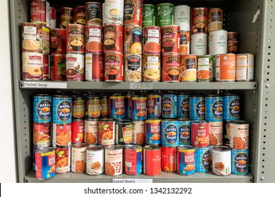 ROTHERHAM, ENGLAND, UK – FEBRUARY 14, 2019: Storage Shelves In A Trussell Trust Local Church Food Bank Warehouse Showing Tins Of Baked Beans And Soup Ready For Food Parcels