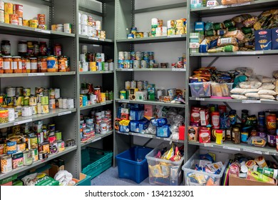 ROTHERHAM, ENGLAND, UK – FEBRUARY 14, 2019: Storage shelves in a Trussell Trust local church food bank warehouse showing a variety of tins and store cupboard essentials ready for food parcels