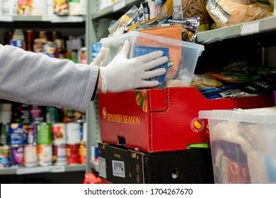 ROTHERHAM, UK - APRIL 14, 2020: A Volunteer At A Trussell Trust Food Bank Wears Gloves PPE In The Coronovirus Pandemic Whilst Packing A Client Parcel