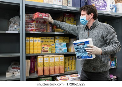 ROTHERHAM, UK - MAY 6, 2020: A Volunteer At A Trussell Trust Food Bank Wears Gloves And Face Mask PPE In The Coronovirus Pandemic Whilst Packing A Client Parcel