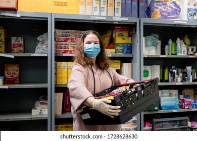 ROTHERHAM, UK - MAY 6, 2020: A Volunteer At A Trussell Trust Food Bank Wears Gloves And Face Mask PPE In The Coronovirus Pandemic Whilst Packing A Client Parcel