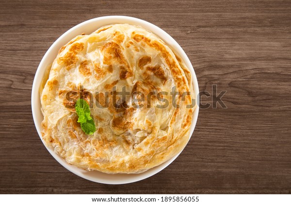 Roti Parata or Roti canai with lamb curry sauce\
- popular Malaysian\
breakfast