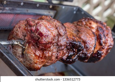 Rotisserie Beef Rotating On A Barbecue Spit Closeup Red Meat On Open Grill Over Hot Coals