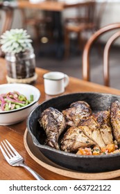 Rotisserie Chicken With Tomatoes In Iron Pan And Nopales Salad In White Enamel Bowl, Mug, Cactus And Chair On The Background.Vertical