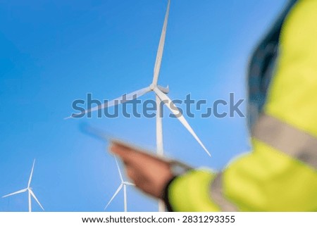 The rotor is centred and clean while everything nearer the lens melts away, a quiet composition that puts the generating machine first and the human gesture second.