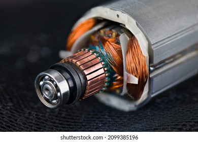 Rotor and stator detail of electric DC motor on black mesh background. Closeup of steel ball bearing, copper commutator or coil wires inside metal laminations of drill machine engine on dark blue net. - Shutterstock ID 2099385196