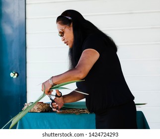 ROTORUA, NEW ZEALAND – JANUARY 7, 2009: Maori woman cutting flax for basket weaving in Rotorua, New Zealand.