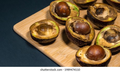 Rotten Avocados Halfs On Table. Bad Fruits On Wood Chipper. Overripe Avocado Close Up.