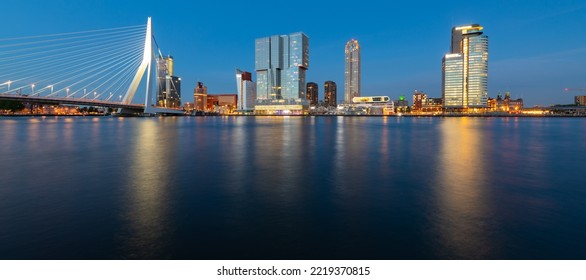 Rotterdam Netherlands Wide Angle Nighttime Panorama With Skyline, Modern Buildings And Iconic Bridge. Evening Sky Reflection In River Maas Harbour At Blue Hour With Colorful Illumination