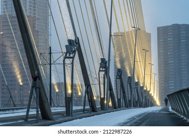 Rotterdam, The Netherlands-February 2021; Low angle view of the Erasmus bridge during early morning snow storm bridge lights shining on the bridge cables showing snow flurries