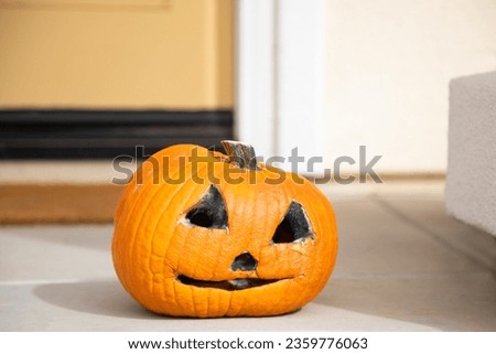 Rotting and moldy Jack-O'-Lantern pumpkin with anthropomorphic face on doorstep  for Halloween celebration.