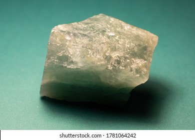 Rough Aquamarine Gemstone On A Green Background.