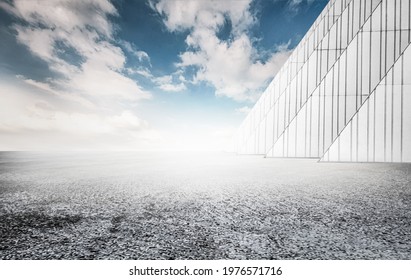 Rough asphalt pavement and white triangular building wall under the blue sky, car advertisement synthetic creative background.