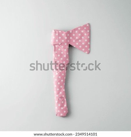 Rough axe packaged in pink polka dot gift paper on a blue background. Top view.  