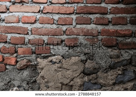 Rough brick wall texture with peeling grey plaster and exposed rocks