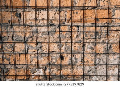 Rough brick wall texture with a protective metal grid covering.