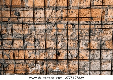Rough brick wall texture with a protective metal grid covering.