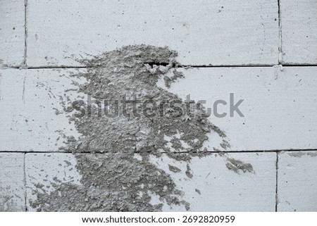 Rough cement patch on white concrete wall showing uneven texture and construction detail.