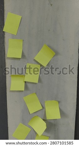 A rough cement wall with a plain yellow paper attached, without any text, creating a minimal and textured urban background. The composition emphasizes raw surface texture, industrial material, simplicity, and color contrast between grey concrete and yellow paper. Ideal for themes such as urban texture, abstract background, construction surfaces, and minimal design